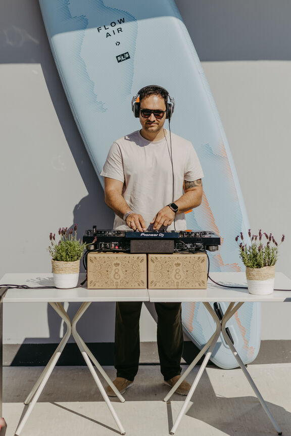 DJ an der Strandbar Ein DJ legt vor einem großen Surfbrett auf
