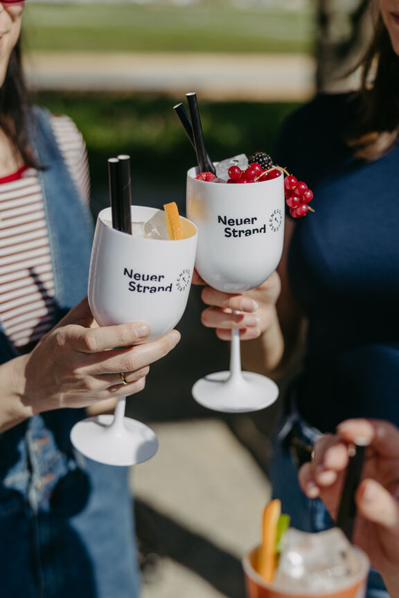 Cocktails an der Strandbar 2 Frauen prosten sich mit Cocktails in weißen Gläsern zu